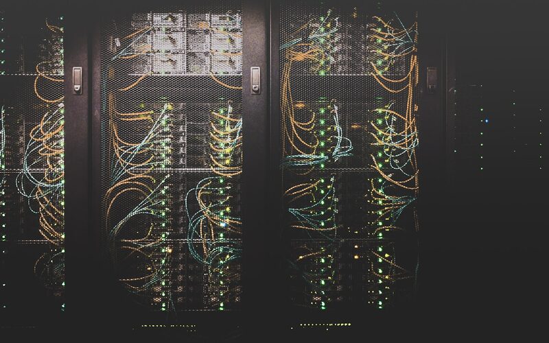 Fiber optic network cabling glowing inside a data centre rack