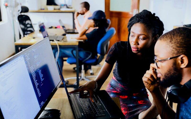 A team member explaining information on a computer screen to a colleague